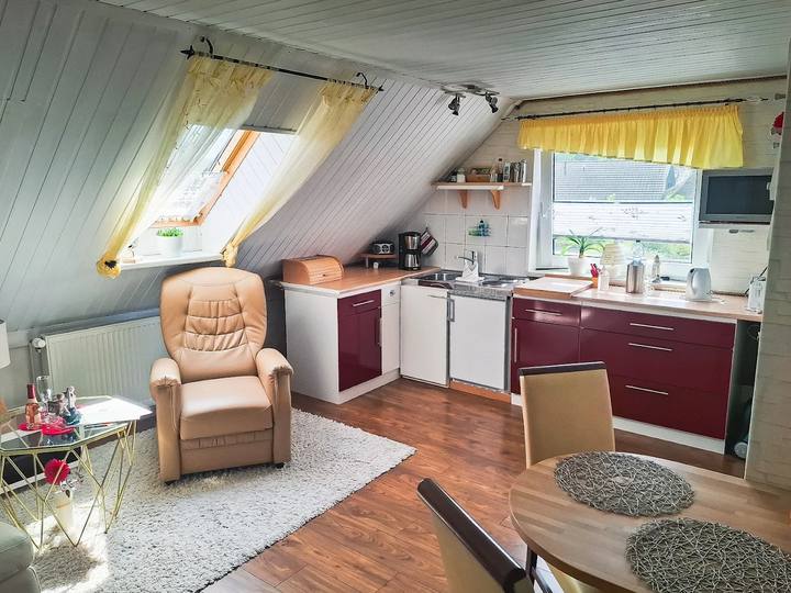 Wohnküche mit Sessel und Essbereich unter der Dachschräge