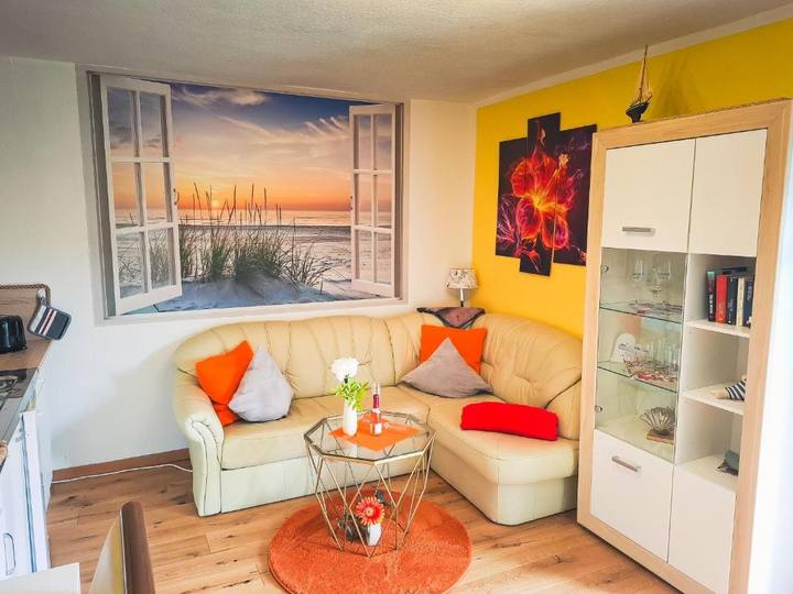 Wohnzimmer mit Eckcouch und Strand-Fensterbild in einer Dachgeschoss-Ferienwohnung