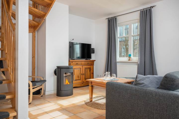 Wohnzimmer mit Kaminofen, Fernseher und Sofa