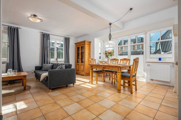 Heller Wohn- und Essbereich mit Sofa, Esstisch und großen Fenstern in einem Ferienhaus